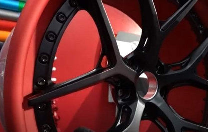 Close-up of black forged aluminum wheel rim with red background designed for Mustang Mach-E
